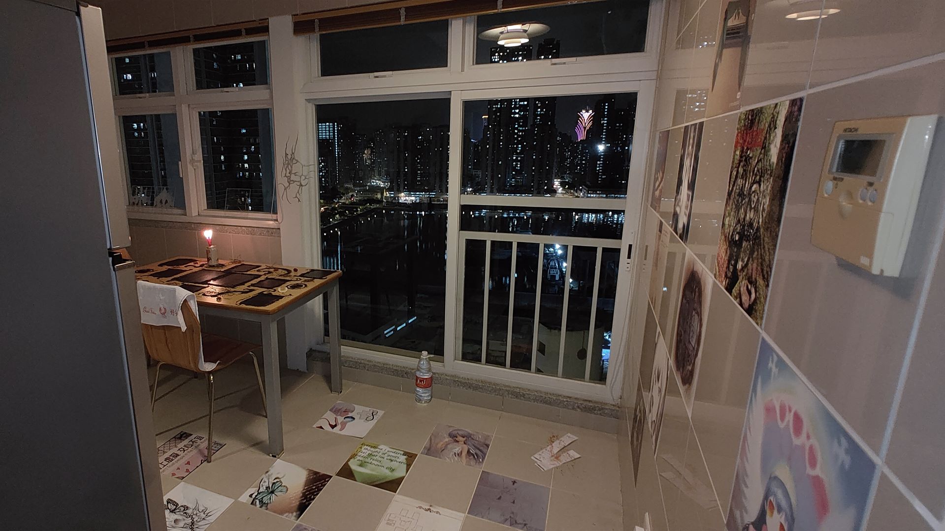 interior of kitchen with wide windows with city peer view. there's a table with black images on top and 1:1 tiles with images