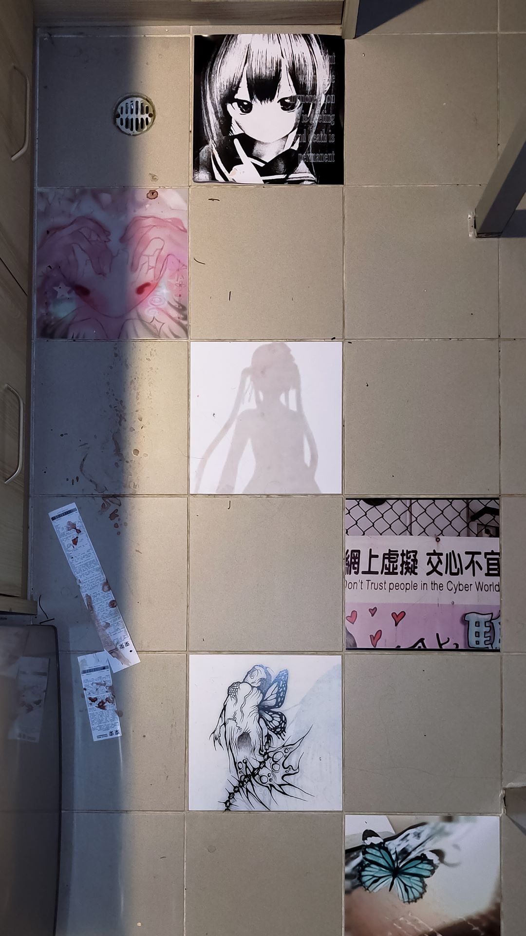 another view of the floor sticker tiles. there's a denpa doll, a pink waifu with red eyes holding her own head, a silhuete of ophelia from cineris somnia, a butterfly and a butterfly creature and one image with hearts and graffity and chinese character in a wired fence saying don't trust people in the cyber world