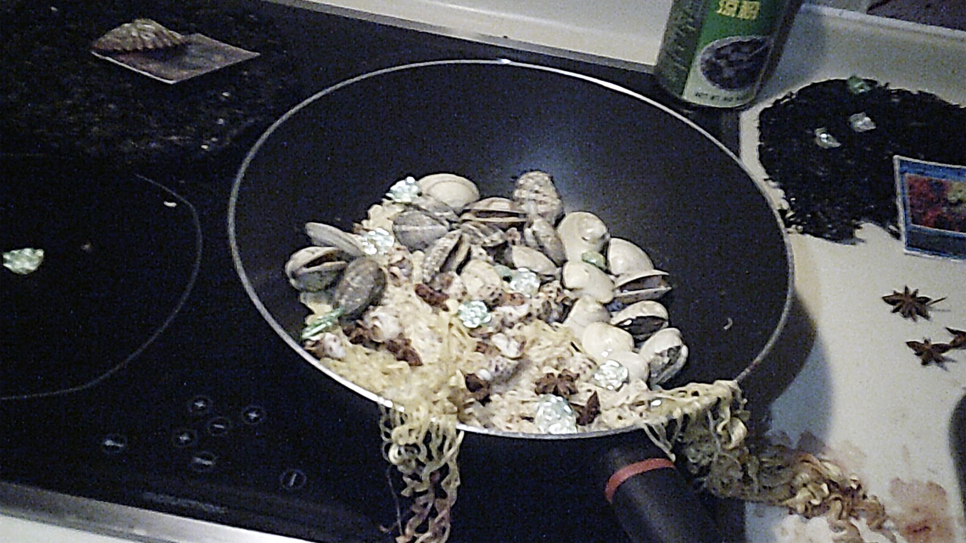 close uo of pan filled with clams, sea shells, noodles and small plastic pearls and roses
